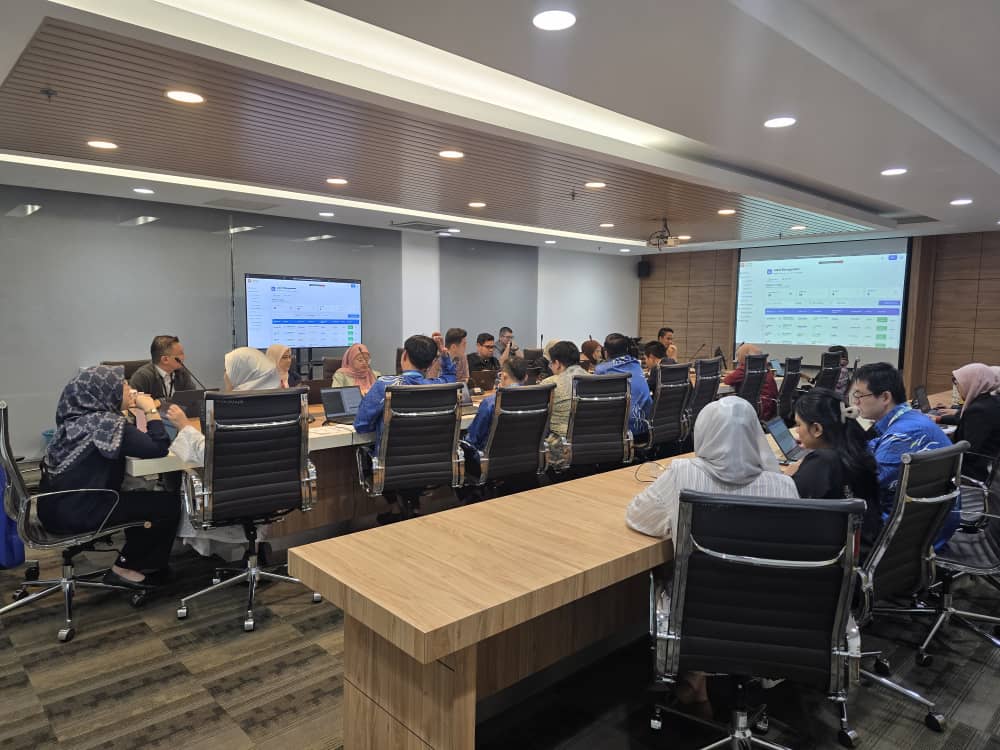 Conference room with two large screens displaying the EIS management dashboard, with attendees on both sides of a long table reviewing the interface.